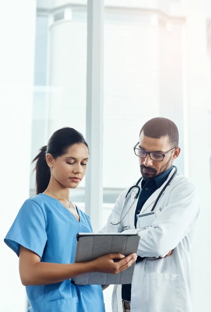 Two healthcare workers reviewing a tablet together