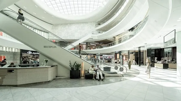 Interior of a multi-level shopping mall with an escalator and shoppers